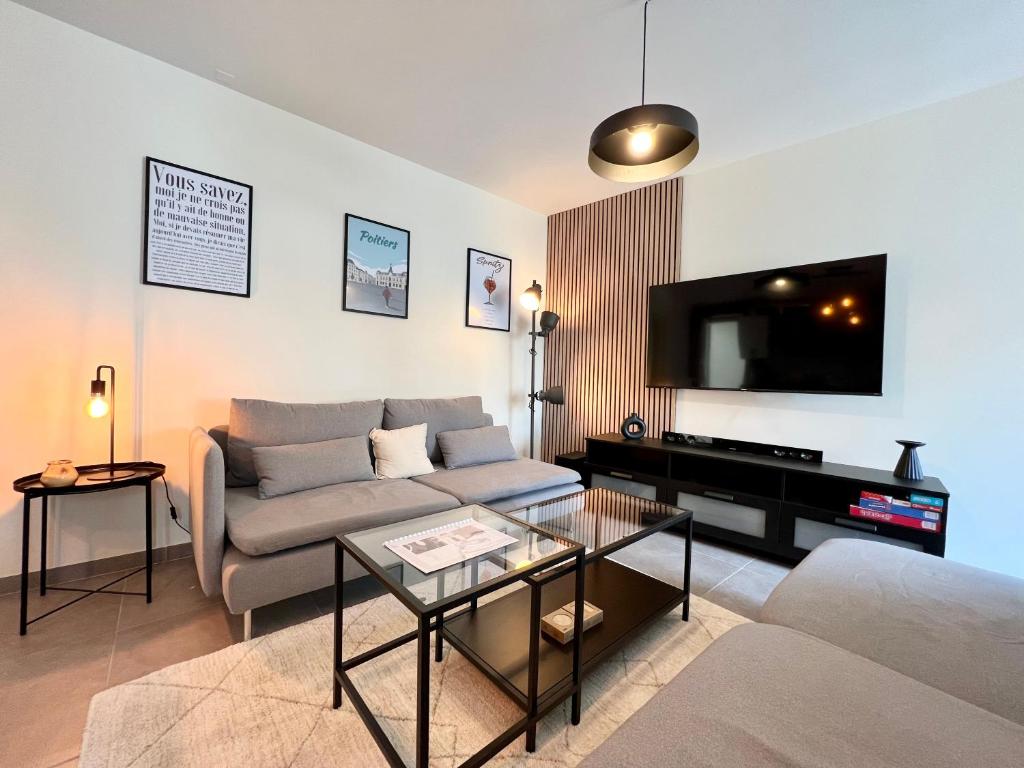 a living room with a couch and a flat screen tv at La parenthèse Chic & Cosy - 8 min du Futuroscope ! in Saint-Georges-lès-Baillargeaux