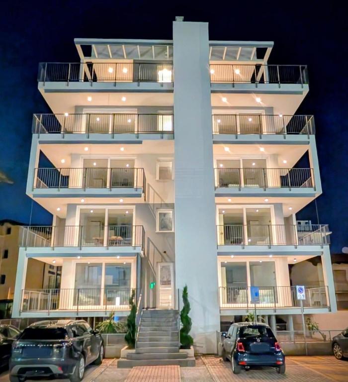 a white building with cars parked in front of it at Jesolo Design Apartments - NEW 2025 - Central near the beach in Lido di Jesolo