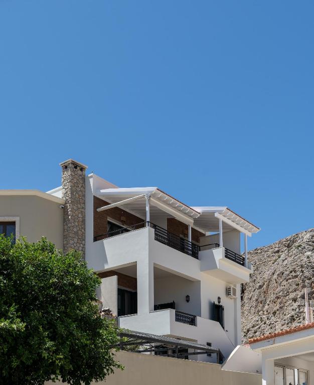 a white apartment building with balconies on a hill at Marys Beachfront Villa in Kalymnos
