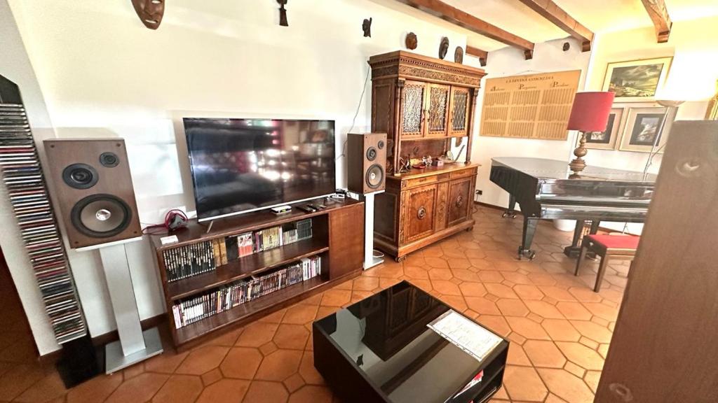 a living room with a television and a piano at Musicians Mansion Apartment in Fino Mornasco