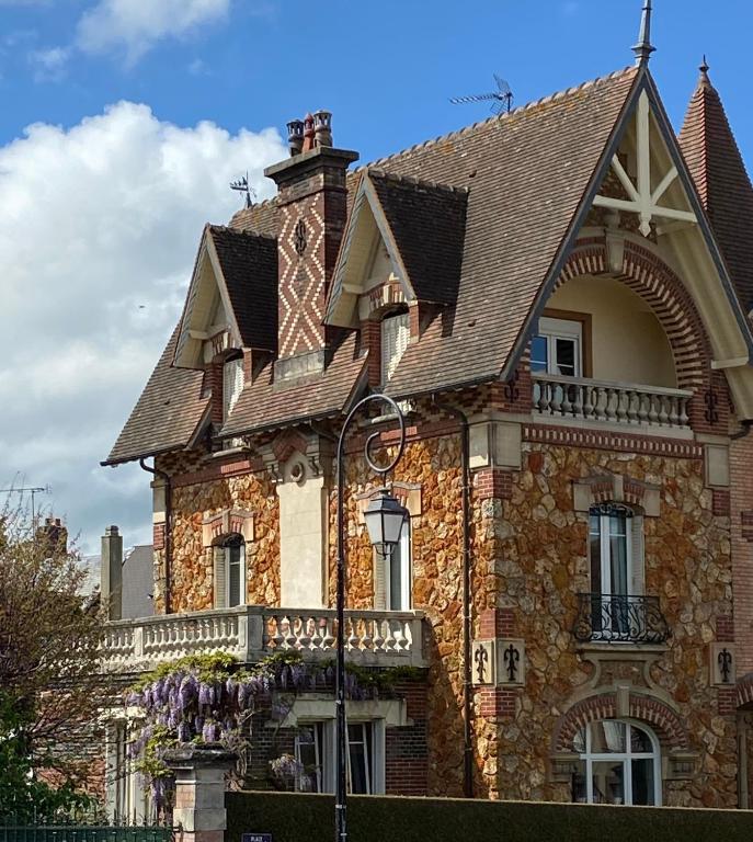 a large brick building with a roof at Le Lierre et La Rose in LʼAigle