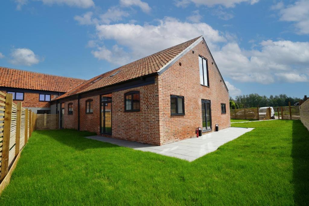un edificio de ladrillo con un patio de hierba delante de él en Rookery Park Barn, en Carlton Colville