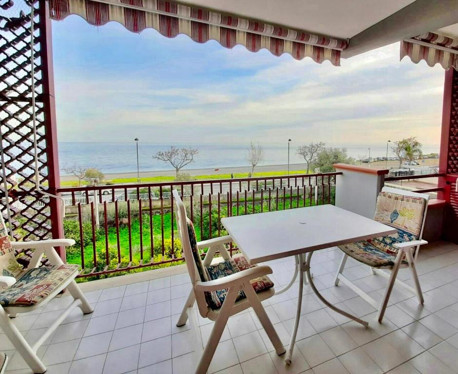 a table and chairs on a balcony with a view of the ocean at Alba sul Mare Apartments in Ali Terme