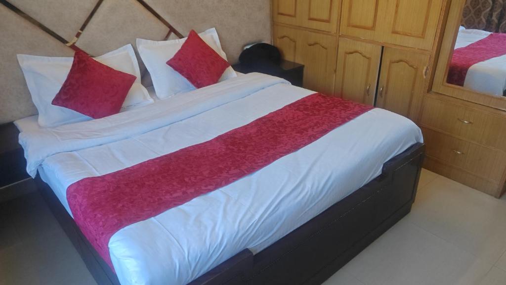 a bedroom with a large bed with red and white pillows at maya guest house in Calangute