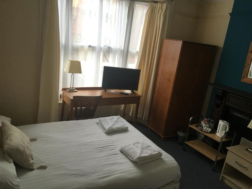une chambre avec un lit et un bureau avec un ordinateur dans l'établissement Four Seasons Budget, à Aberystwyth