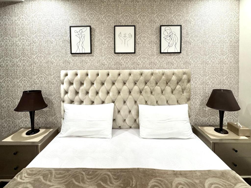 a bedroom with a bed with three pictures on the wall at Lux Haven Stays 2 Bedroom Luxury Apartment Near Gulberg - Ultimate Getaway Experience in Lahore