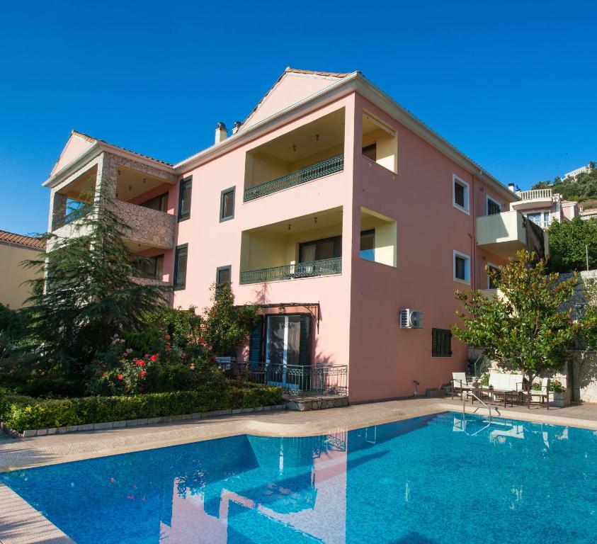 a villa with a swimming pool in front of a building at Pirofani Villa Apartments in Apolpaina