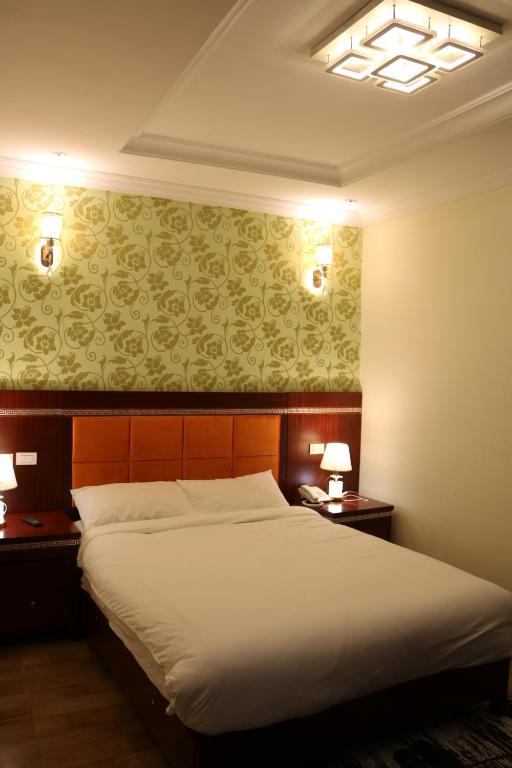 une chambre avec un grand lit et deux tables de nuit dans l'établissement Tilman Hotel, à Addis-Abeba