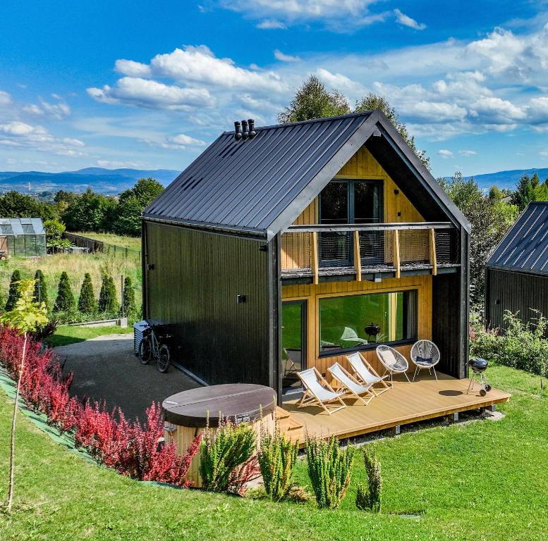 a small house with a deck and chairs in the yard at Domki Salamandra Lipowa in Lipowa