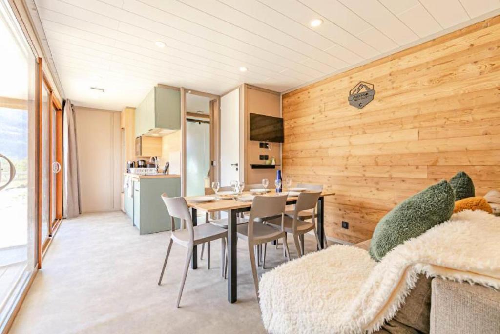una sala da pranzo con tavolo e sedie e una cucina di Résidence Camping La Buidonniere - Chalet confortable et lumineux en pleine nature MAE-1033 ad Aussois