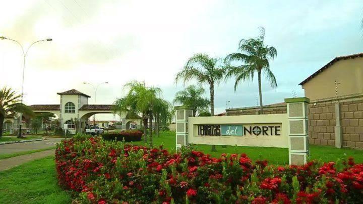 a sign for a hotel next to some flowers at Alojamiento en Terrazas Del Norte Tipuro Maturin in Maturín