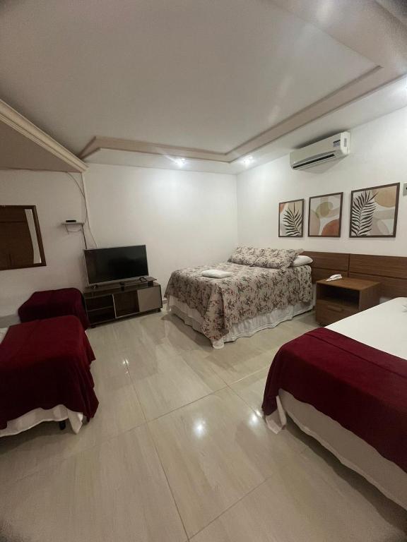 Una habitación de hotel con dos camas y un televisor. en HOTEL POUSADA ALAGOINHAS, en Alagoinhas