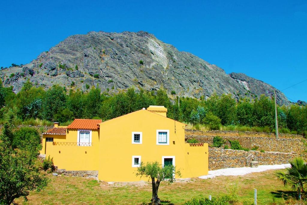 a yellow house in front of a mountain at Quinta da Figueirinha in Marvão