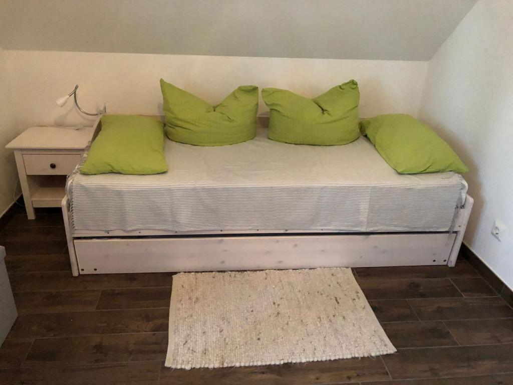 Una cama con almohadas verdes en una habitación pequeña. en Ferienhaus Karola, en Kolpinsee