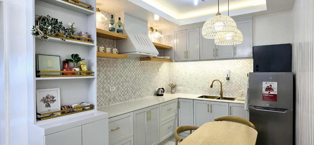 eine Küche mit weißen Schränken und einem Edelstahlkühlschrank in der Unterkunft 2BR Penthouse SMDC Wind Residences Tagaytay in Kaybagal