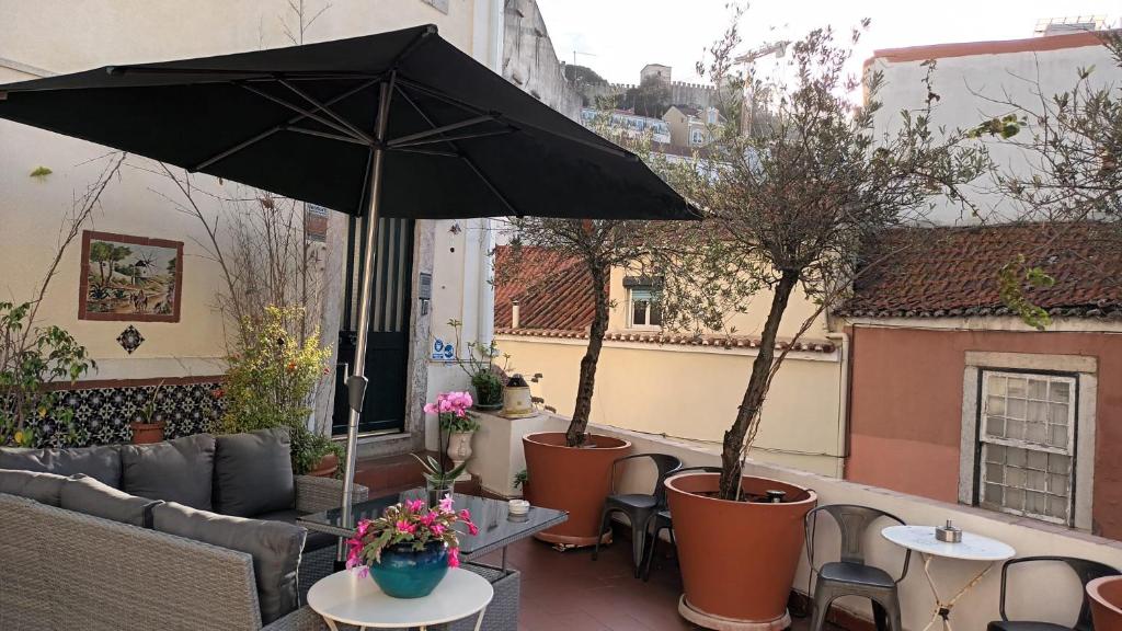 eine Terrasse mit Sonnenschirm und Tischen und Stühlen in der Unterkunft Costa do Castelo Terrace, em Rua dos Lagares 8 in Lissabon