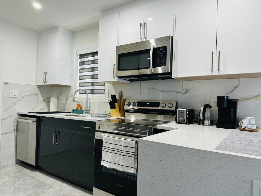 een keuken met roestvrijstalen apparatuur en witte kasten bij Cozy 2 bedroom suite Pet Friendly Heated Garage in Edmonton