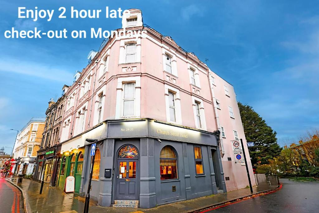 ロンドンにあるChurch Street Hotel by Belvilla near The Oval Londonの看板のある通りにあるピンク色の建物