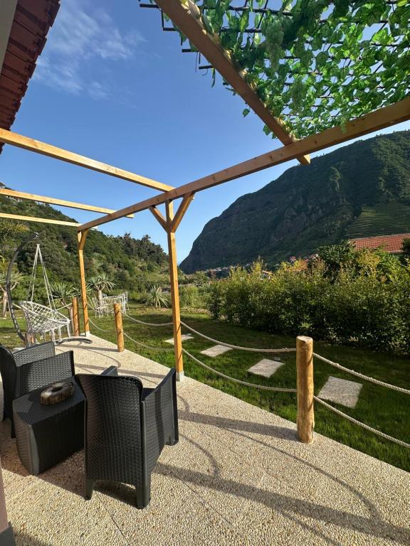eine Terrasse mit Tisch und Stühlen und Blick auf einen Berg in der Unterkunft The Green Valley House II in São Vicente
