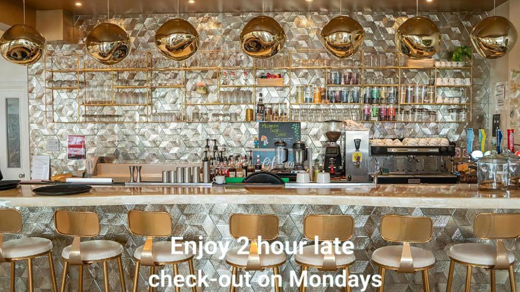 Un bar con una pared de piedra y taburetes dorados. en The Feather&#39;s Hotel Newquay, en Newquay