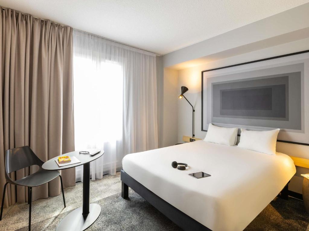 Una habitación de hotel con una gran cama blanca y una mesa. en ibis Strasbourg Centre Gare, en Estrasburgo