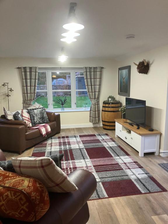 a living room with a couch and a tv at Struan Cottage in Ballater