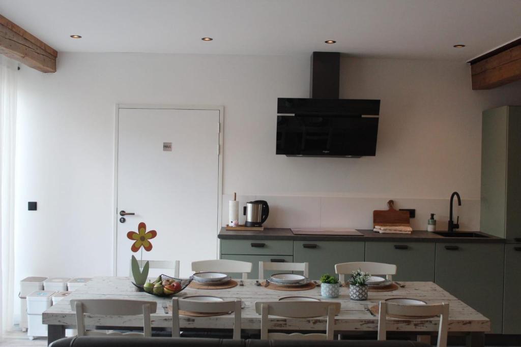 a kitchen with a wooden table and chairs in a room at Vakantie boerderij Pepinushof - 't Hofje in Maria-Hoop