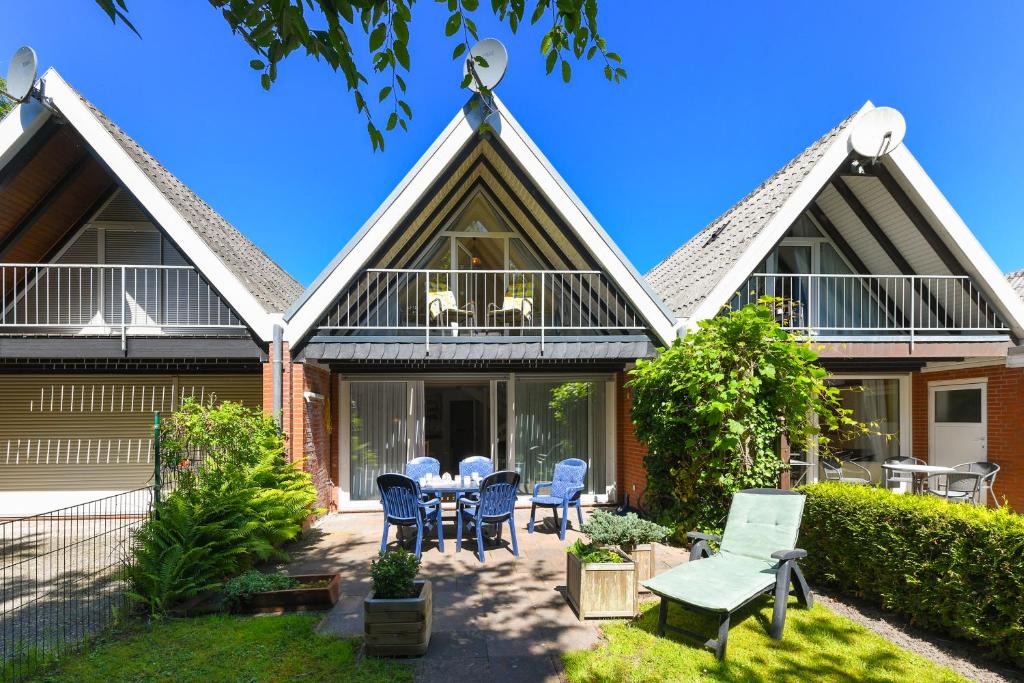 a house with a table and chairs in the yard at Ferienhaus Deichliebe in Bensersiel