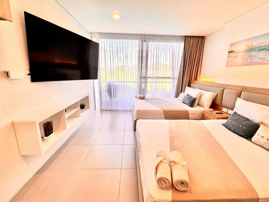 une chambre d'hôtel avec deux lits et une télévision à écran plat dans l'établissement Modern apartment near the beach, à Santa Marta