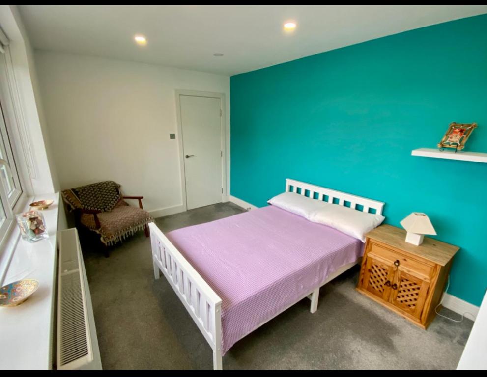 a bedroom with a bed and a blue wall at Modern private room in London
