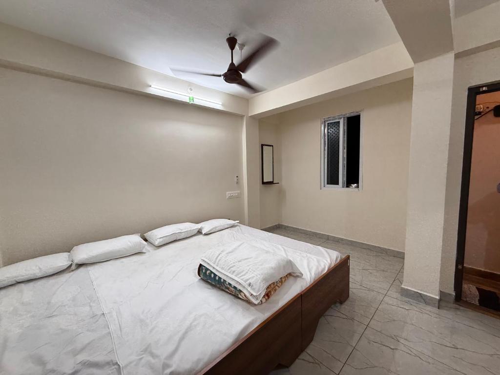 a bedroom with a bed with white sheets and a ceiling at HPS Residency in Velankanni