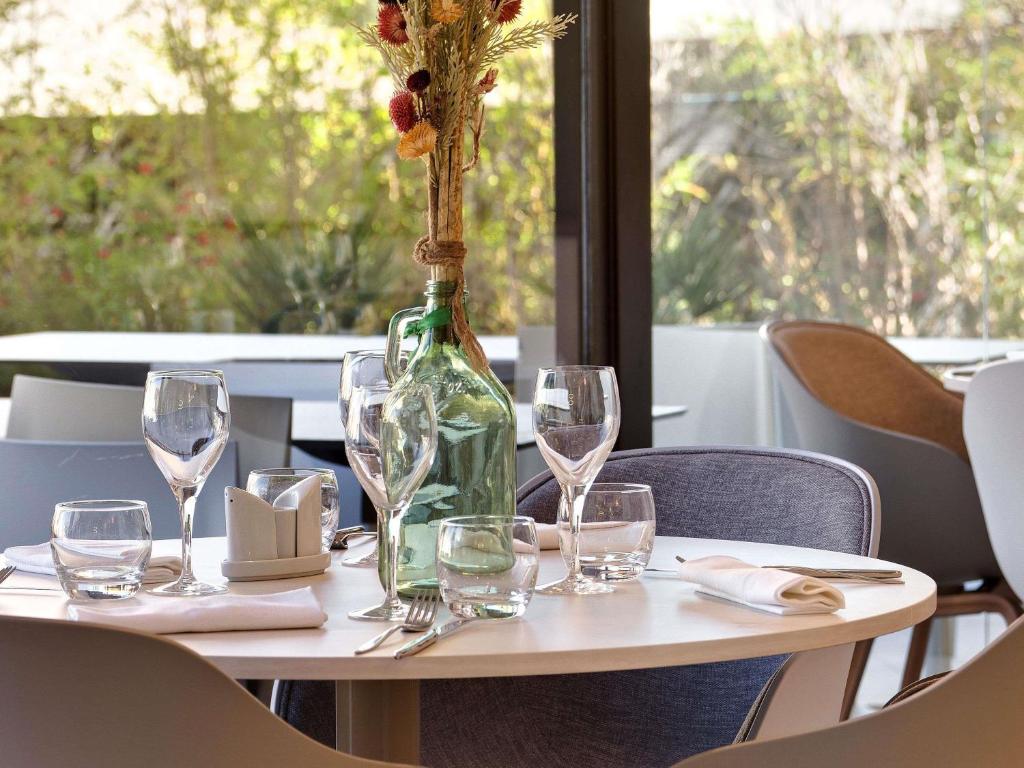 ein Tisch mit Weingläsern und einer Flasche mit einer Vase in der Unterkunft Mercure Montpellier Centre Comédie in Montpellier