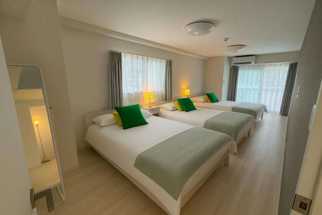 a room with three beds with green pillows at TOEI BUSSAN Building20 in Osaka