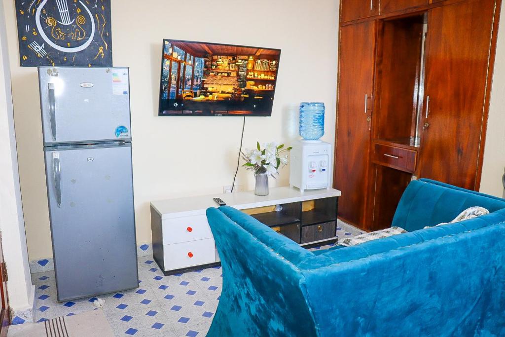 sala de estar con 2 sillas azules y nevera en Little escalade, en Mombasa