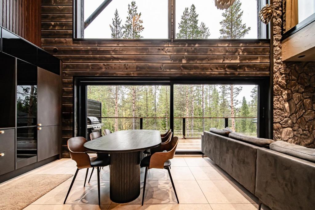 une salle à manger avec une table et des chaises et une grande fenêtre dans l'établissement Villa Komia Iso by Aavalevi, à Levi