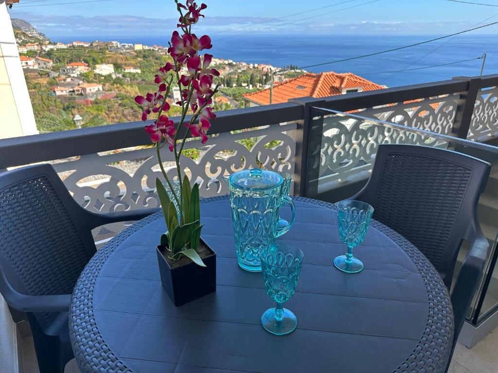 a blue table with glasses and flowers on a balcony at Madeira Inn Refúgio Ponta do Sol in Ponta do Sol