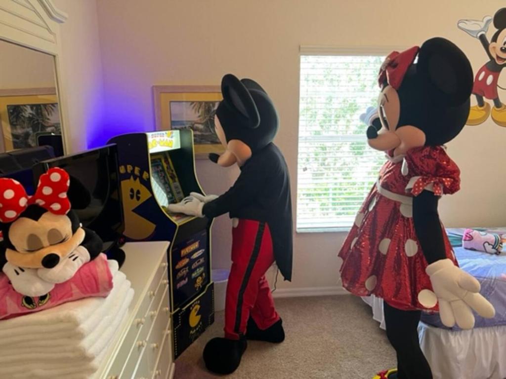 due persone sono in piedi in una camera da letto con i costumi di Topolino di Disney Area Vacation Kissimmee a Kissimmee