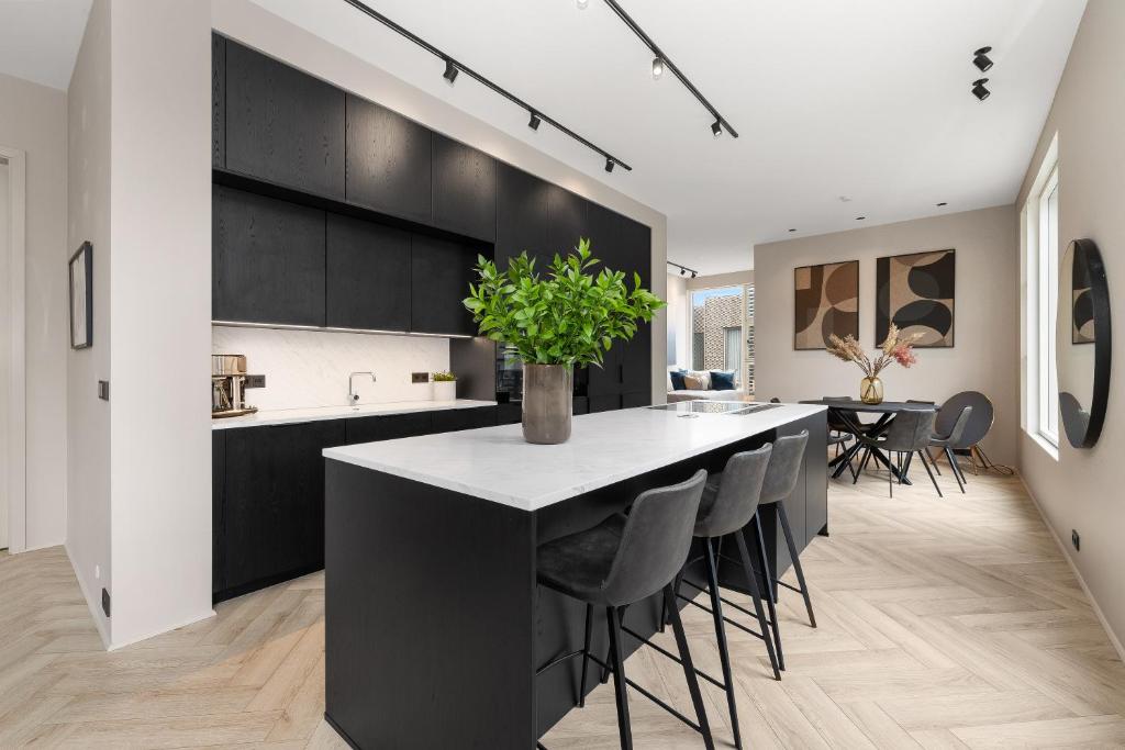 レイキャビクにあるMost Desirable Penthouse in Reykjavíkの黒いキャビネット付きのキッチン、椅子付きのキッチンアイランド
