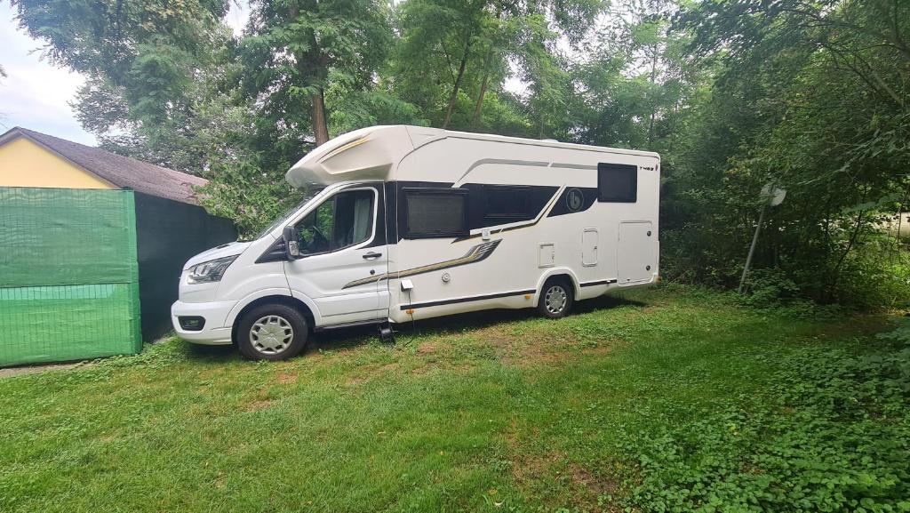 a white camper van parked in a yard at Camping: bring your tent or van in Feldkirchen bei Graz