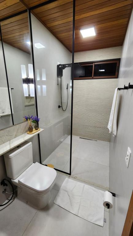 a white bathroom with a shower and a toilet at Chalé Vivenda dos Ventos in Serra de São Bento