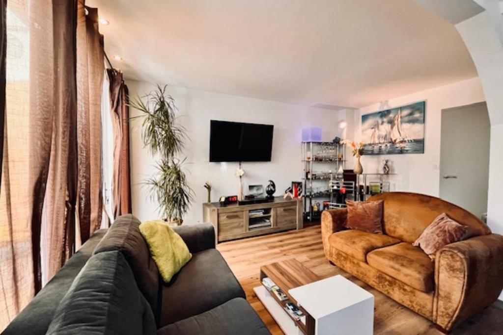 Una sala de estar con un sofá y un televisor. en Spacious house in La Rochelle near the beaches, en Vautreuil