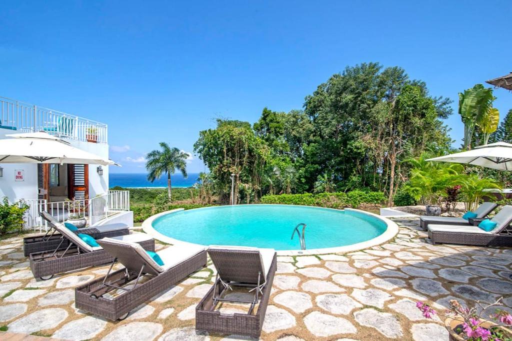 a swimming pool with two lawn chairs and umbrellas at Hospitality Expert HALF HILL Pool Beach in Montego Bay