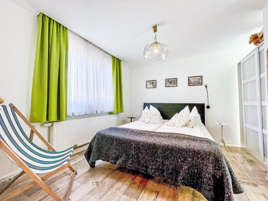 a bedroom with a bed with green curtains and a chair at Apartment Ferienwohnung Naturblick Karla Rößler by Interhome in Grüna