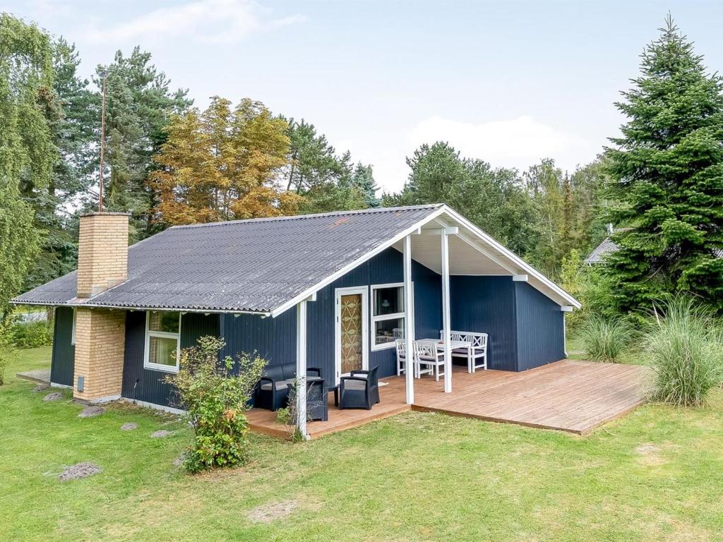 a blue house with a wooden deck in a yard at Holiday Home Aleth - 800m from the sea by Interhome in Gedesby