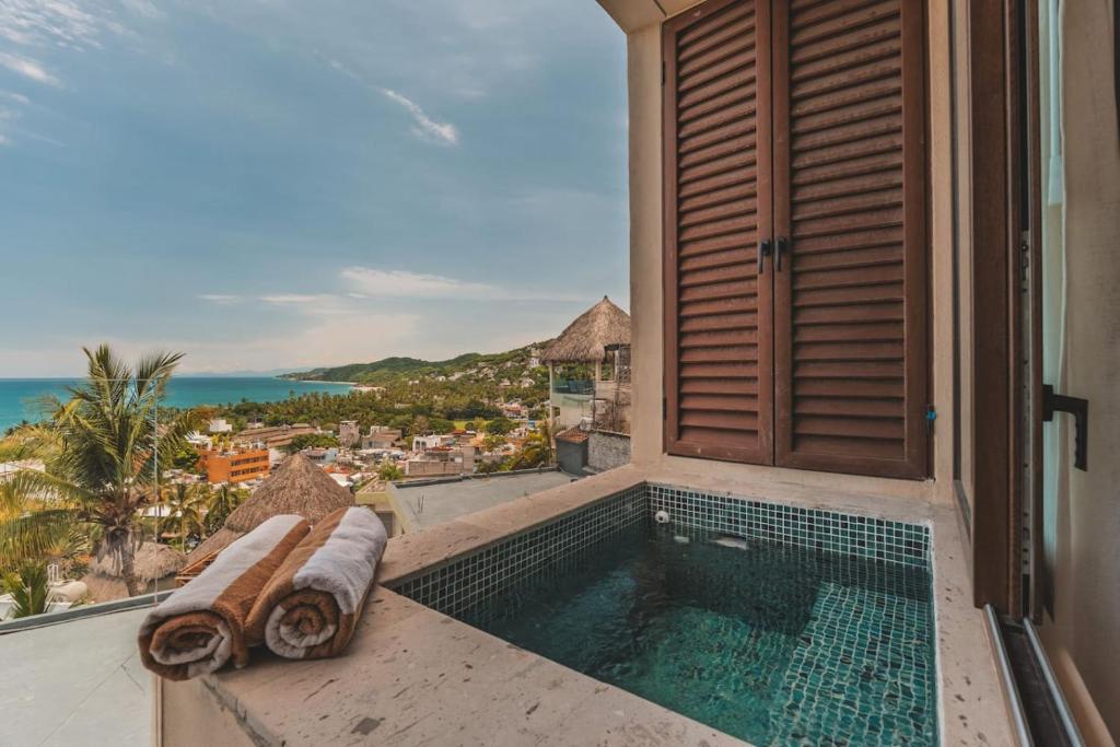 a balcony with a swimming pool and a view of the ocean at Elite 2BR 2BA Ocean Views Rooftop Pool in Sayulita
