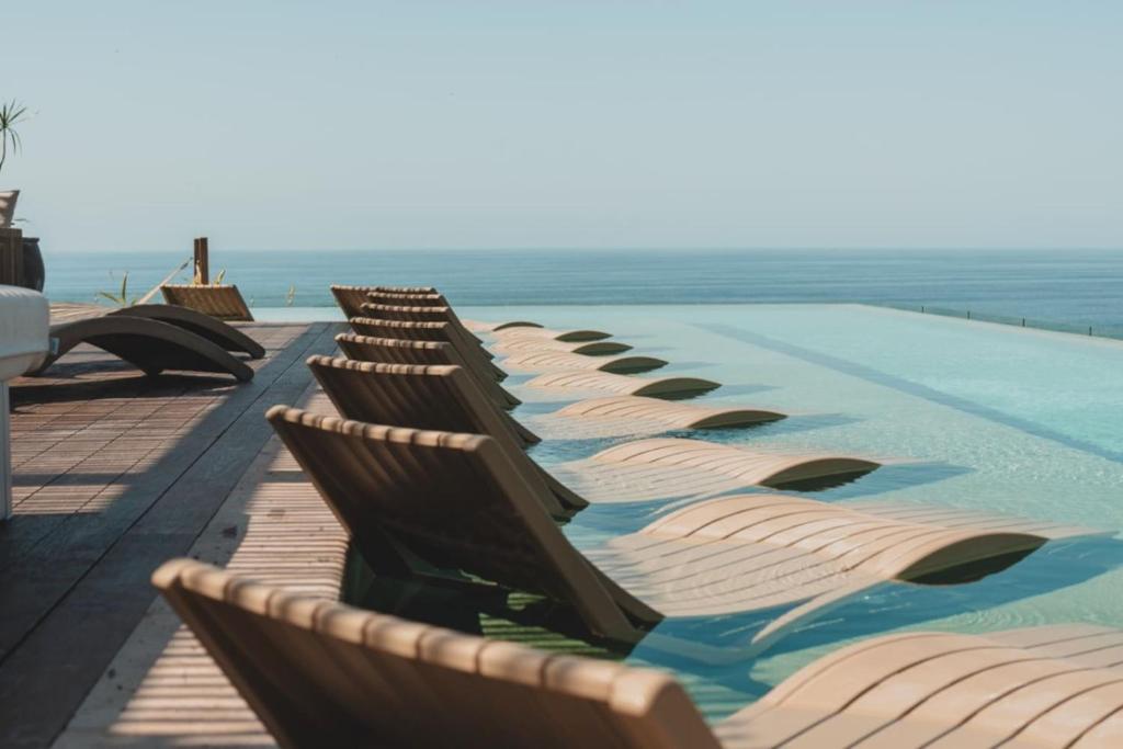 a row of chairs sitting next to a swimming pool at Designer Penthouse with Plunge Pool in Sayulita