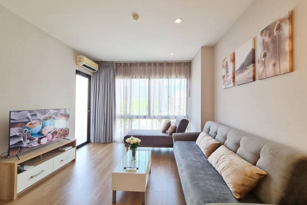 チェンマイにあるSpecious Condo At Nimman With Rooftop Poolのソファとテレビのあるリビングルーム