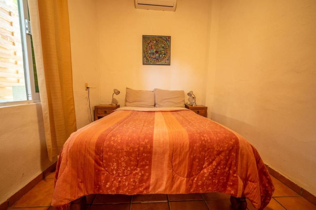 ein Schlafzimmer mit einem Bett mit einer orangefarbenen Decke in der Unterkunft Casa Happy Sol Cangrejo Pool Surf Relax in San Francisco