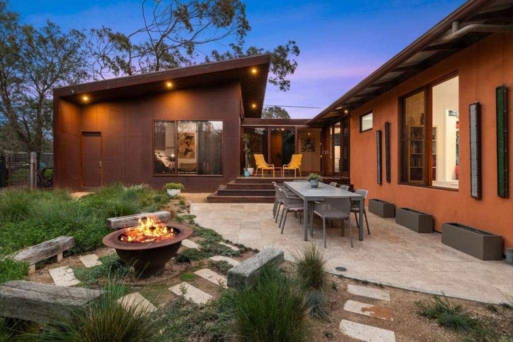 una casa con un patio con una mesa y una fogata en Barnett Bush Retreat, en Torquay