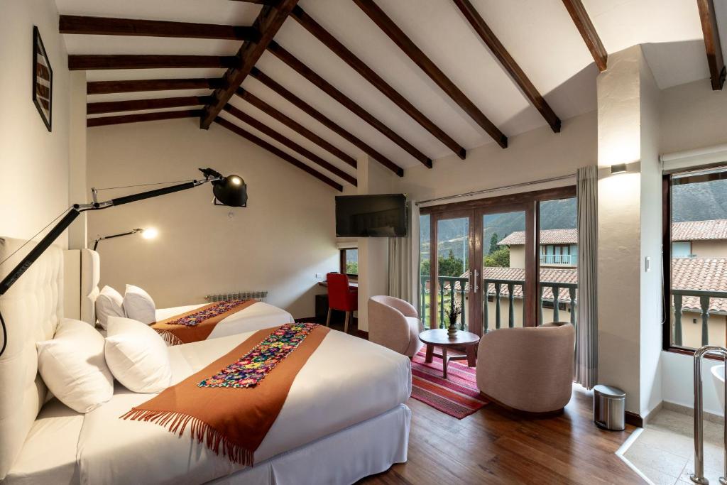 a bedroom with two beds and a balcony at Casa Eva Hotel Boutique in Urubamba